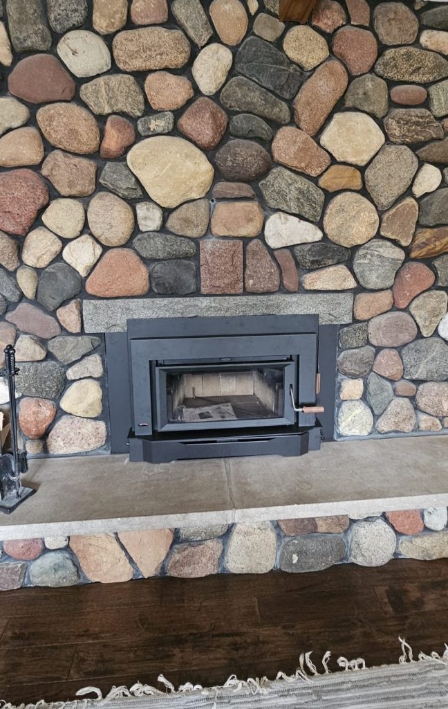 Original photo from The Fire Factory of a wood insert with a stone surround and rug.