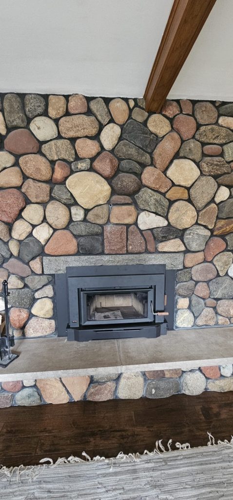 Original photo from The Fire Factory of a wood insert with a stone surround and rug.
