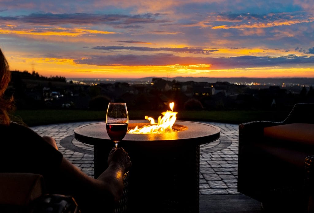 Stock image of a homeowner enjoying a relaxing sunset by their fire pit.